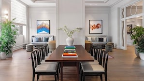 A spacious dining area with a long wooden table, multiple chairs, and a vase with flowers.