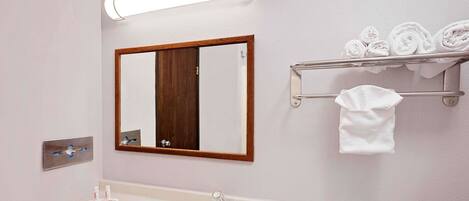 Un baño con lavamanos, espejo, toallero e iluminación.