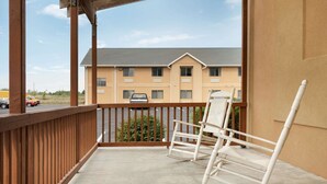 A balcony with a concrete floor, wooden railing, and two rocking chairs.