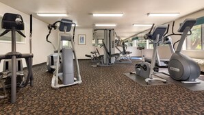 A gym with various exercise equipment including treadmills, elliptical machines, and weight machines.