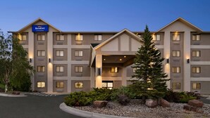 A multi-story hotel with a prominent 'Baymont by Wyndham' sign, a covered entrance, and a landscaped front yard with rocks and shrubs. - Baymont by Wyndham Elko (Elko)