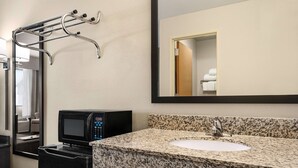 A hotel bathroom with a granite countertop sink, a built-in microwave, and a towel rack. - Baymont by Wyndham Elko (Elko)