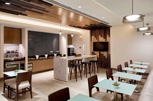 Un restaurante moderno con una barra central, varias zonas de estar y un televisor de pantalla plana en la pared.