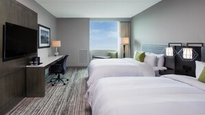 Habitación de hotel con dos camas, un escritorio, una televisión y ventana con vistas.