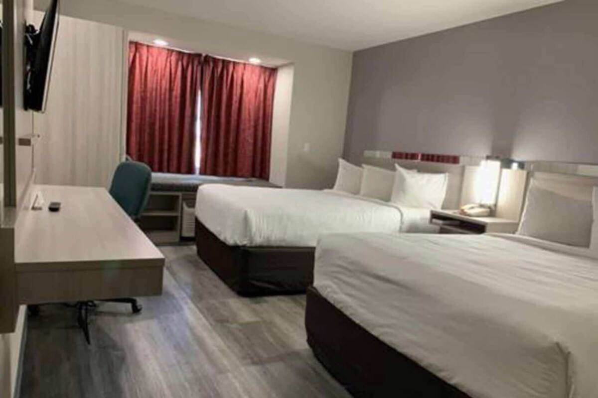 Ein Hotelzimmer mit zwei Betten, einem Schreibtisch, einem Stuhl und einem Fernseher.