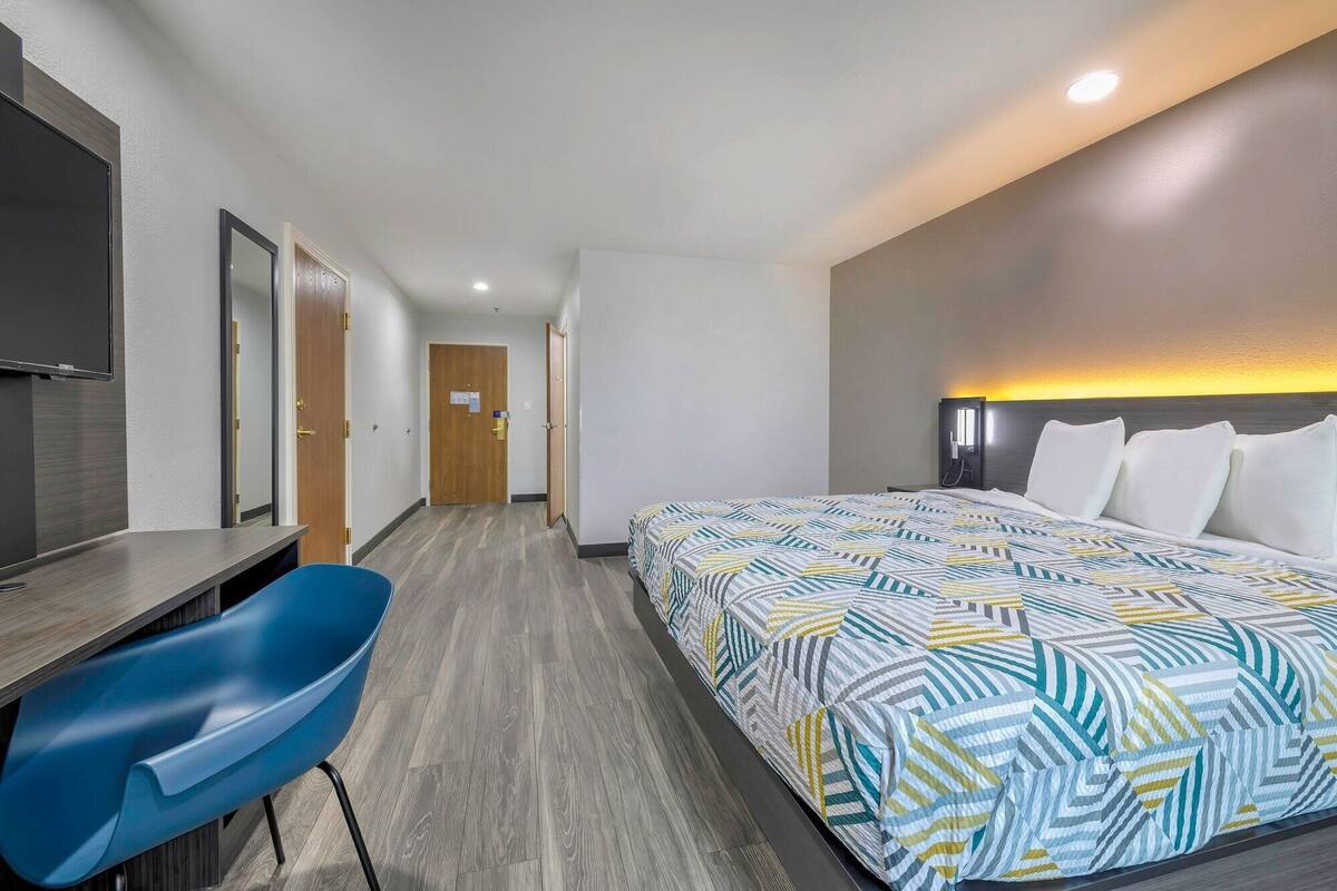 A hotel room with a bed, a desk, and a chair.