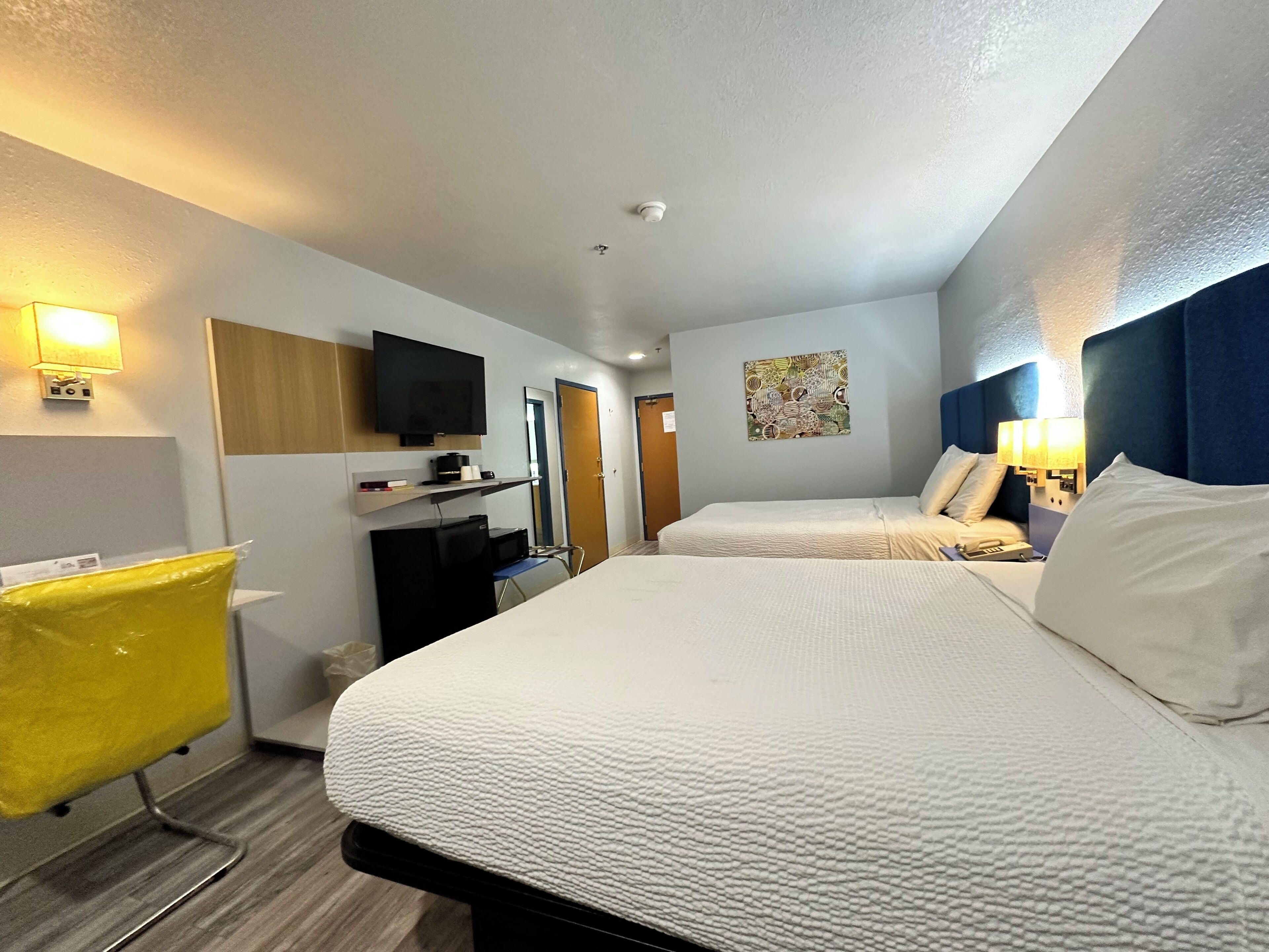 A hotel room with two beds, a television, a desk with a computer, and a bathroom.