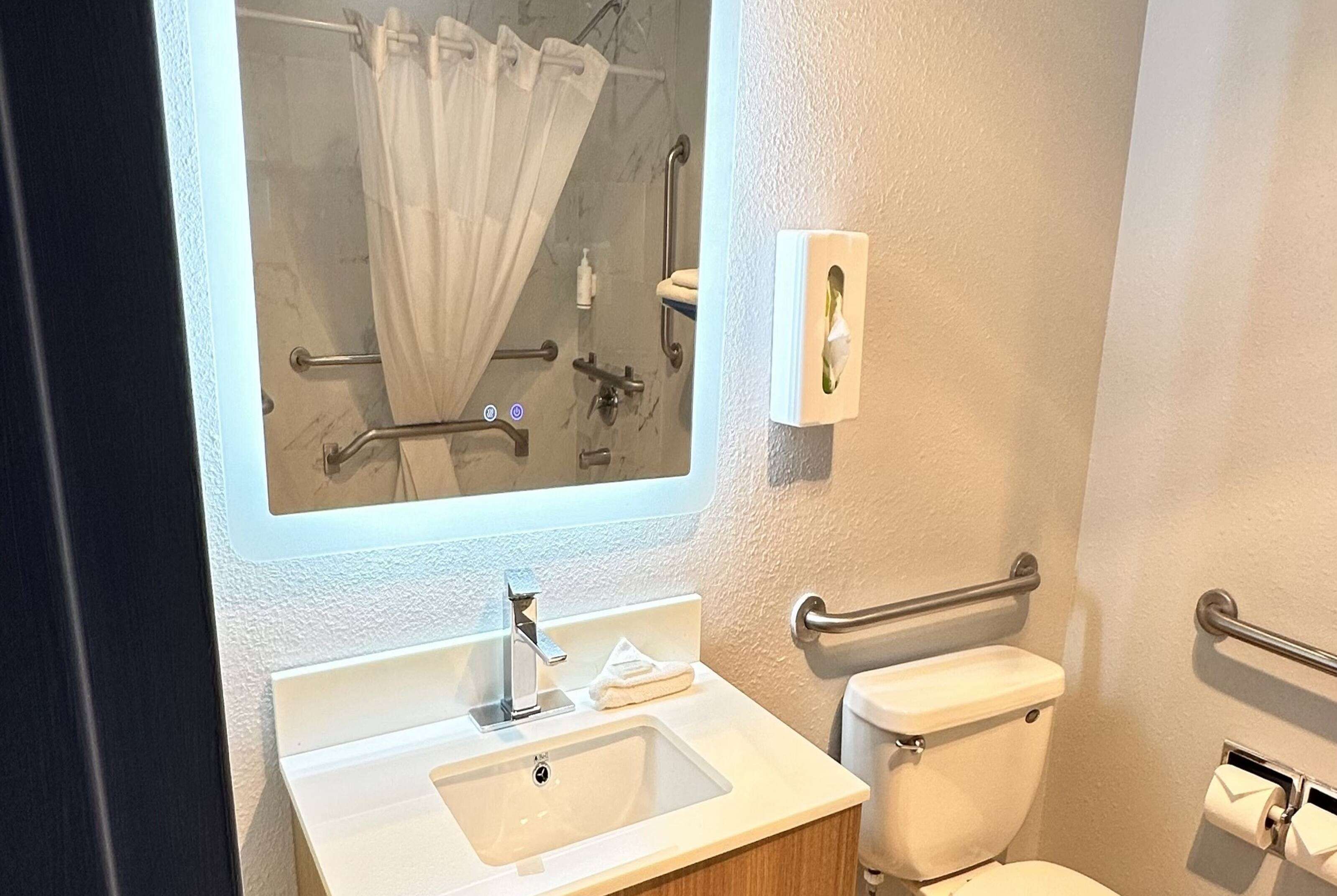 A bathroom with a white sink, a mirror, a toilet, and a shower area.