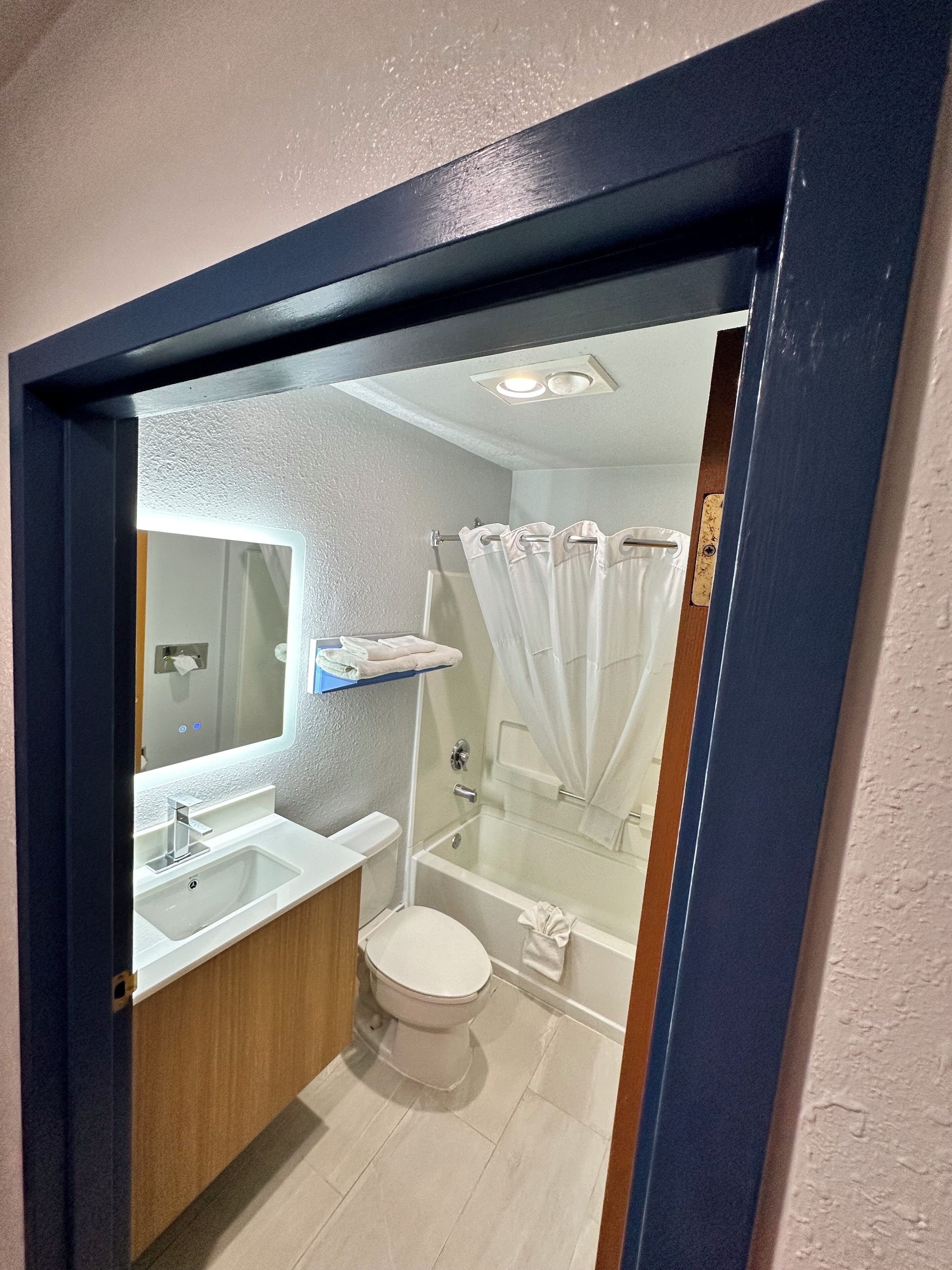 Un bagno moderno con lavandino, servizi igienici e zona doccia, tutti in bianco.