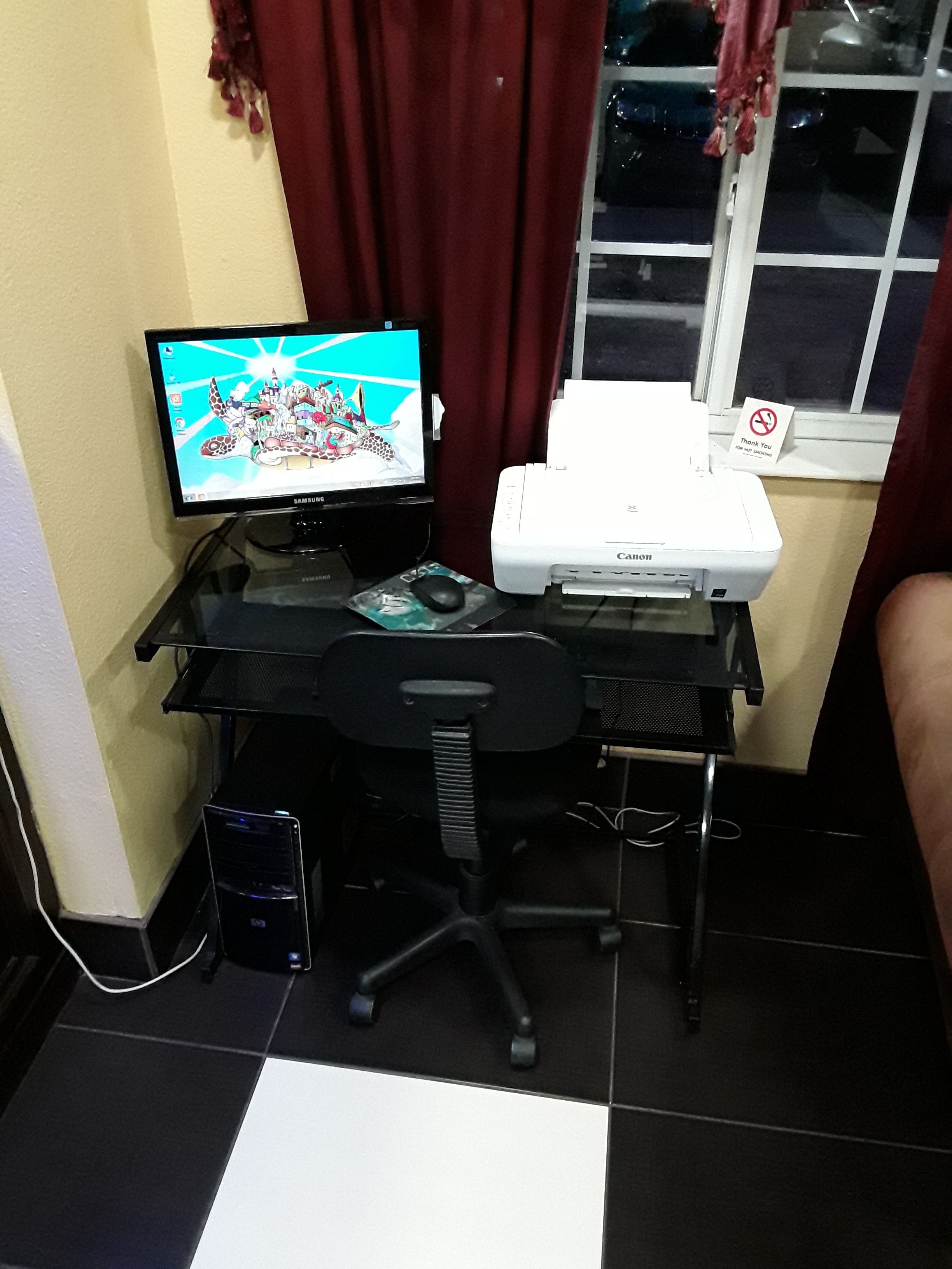 Un espacio de trabajo en casa con una computadora de escritorio, monitor, impresora y silla de oficina.