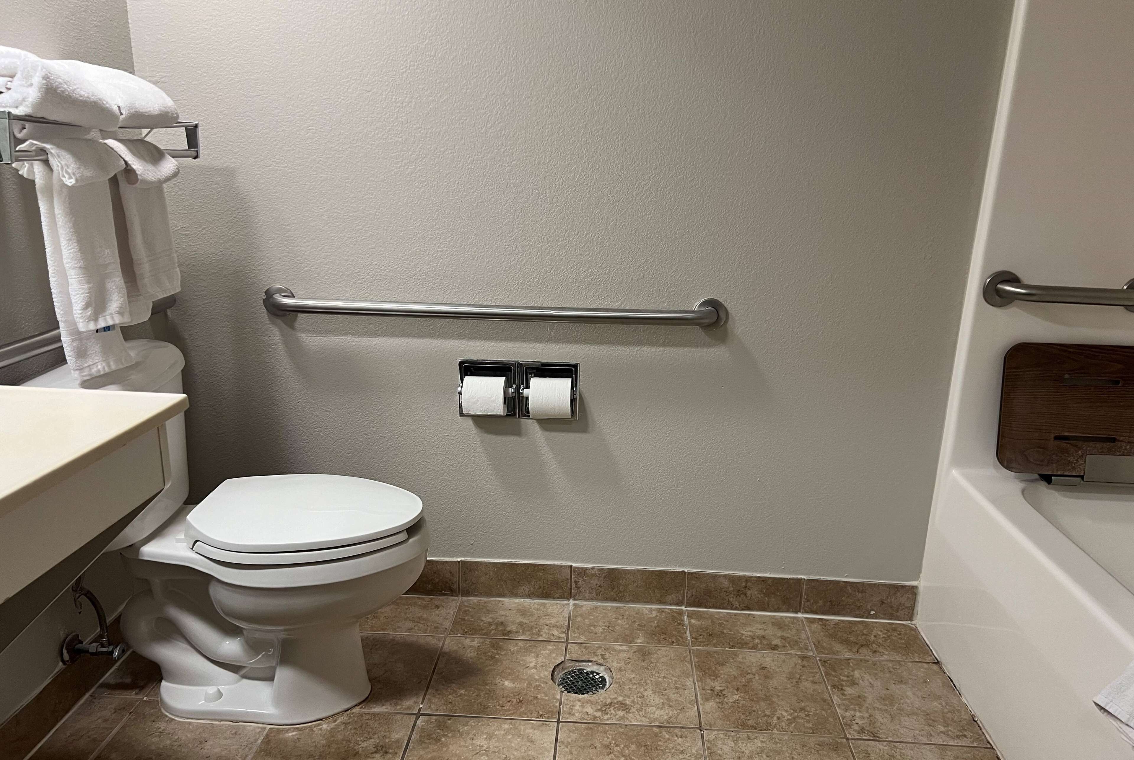 A bathroom with a toilet, a towel rack, a grab bar, and a toilet paper holder.
