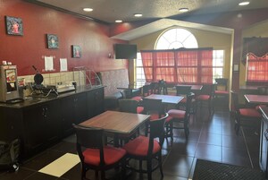 Interior de un restaurante con mostrador, zona de asientos y un amplio ventanal.