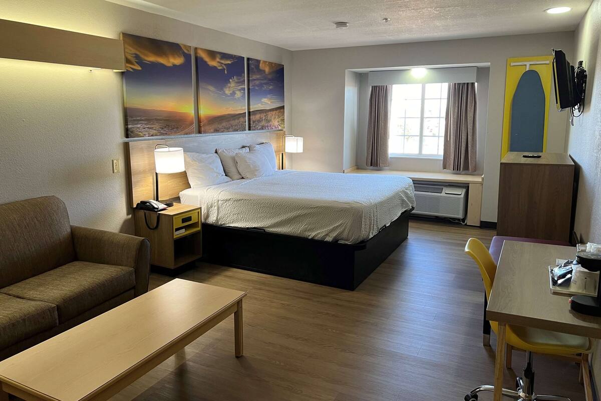Een hotelkamer met een bed, een bank, een bureau en een raam met gordijnen.