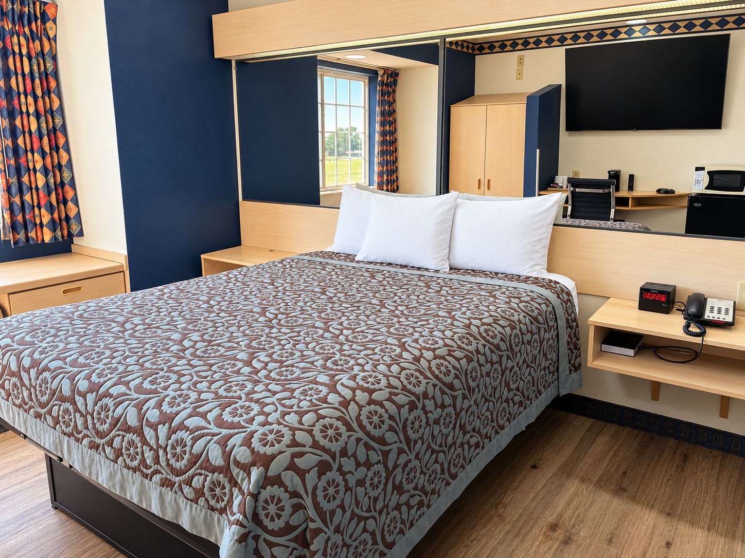 Une chambre d’hôtel équipée d’un lit, d’un bureau avec un ordinateur, d’une télévision et d’un téléphone.