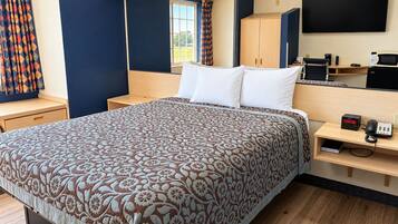 Une chambre d’hôtel équipée d’un lit, d’un bureau avec un ordinateur, d’une télévision et d’un téléphone.