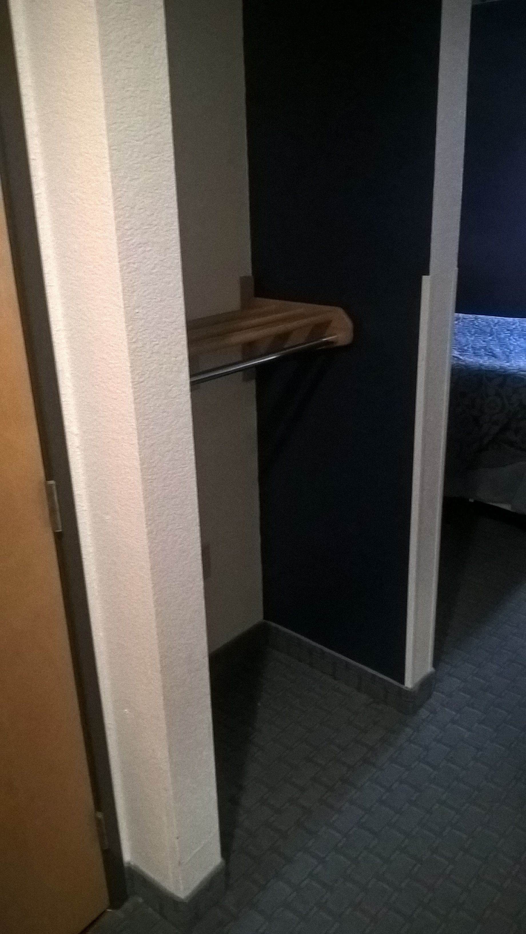 A narrow hallway with a wooden door on the left and a dark wall on the right.