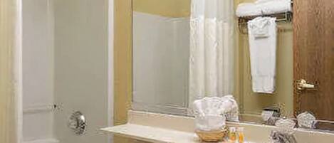 Un baño con lavamanos blanco, un espejo y zona de ducha.