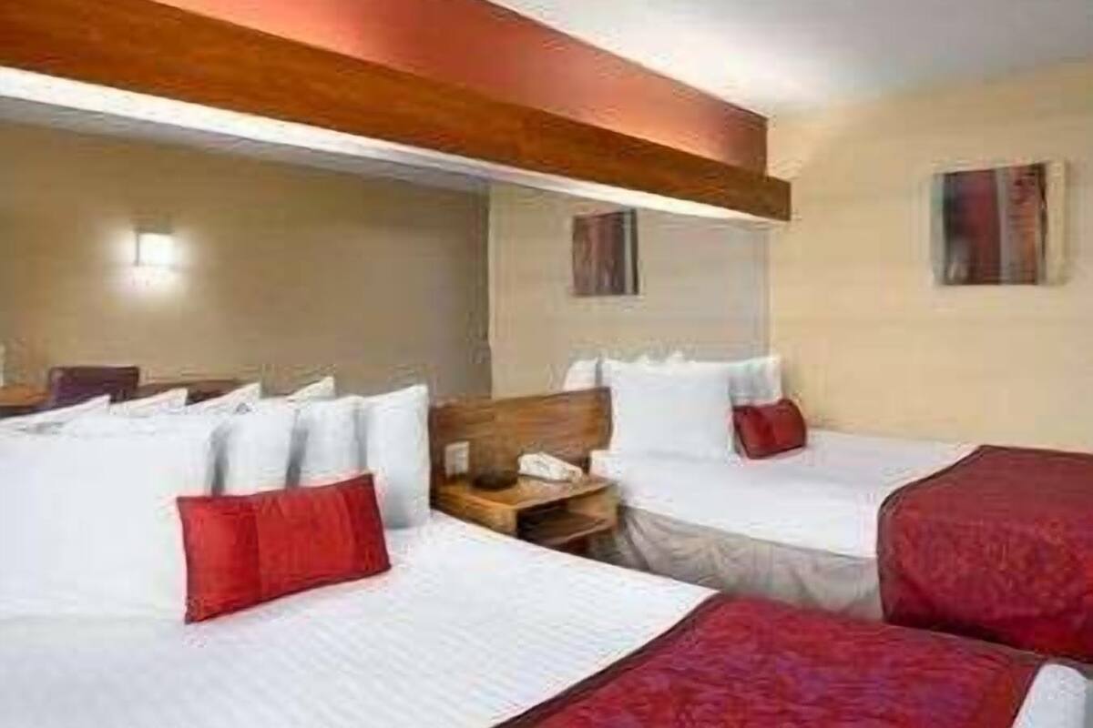 A hotel room with two beds, a wooden headboard, a nightstand, and a mirror.