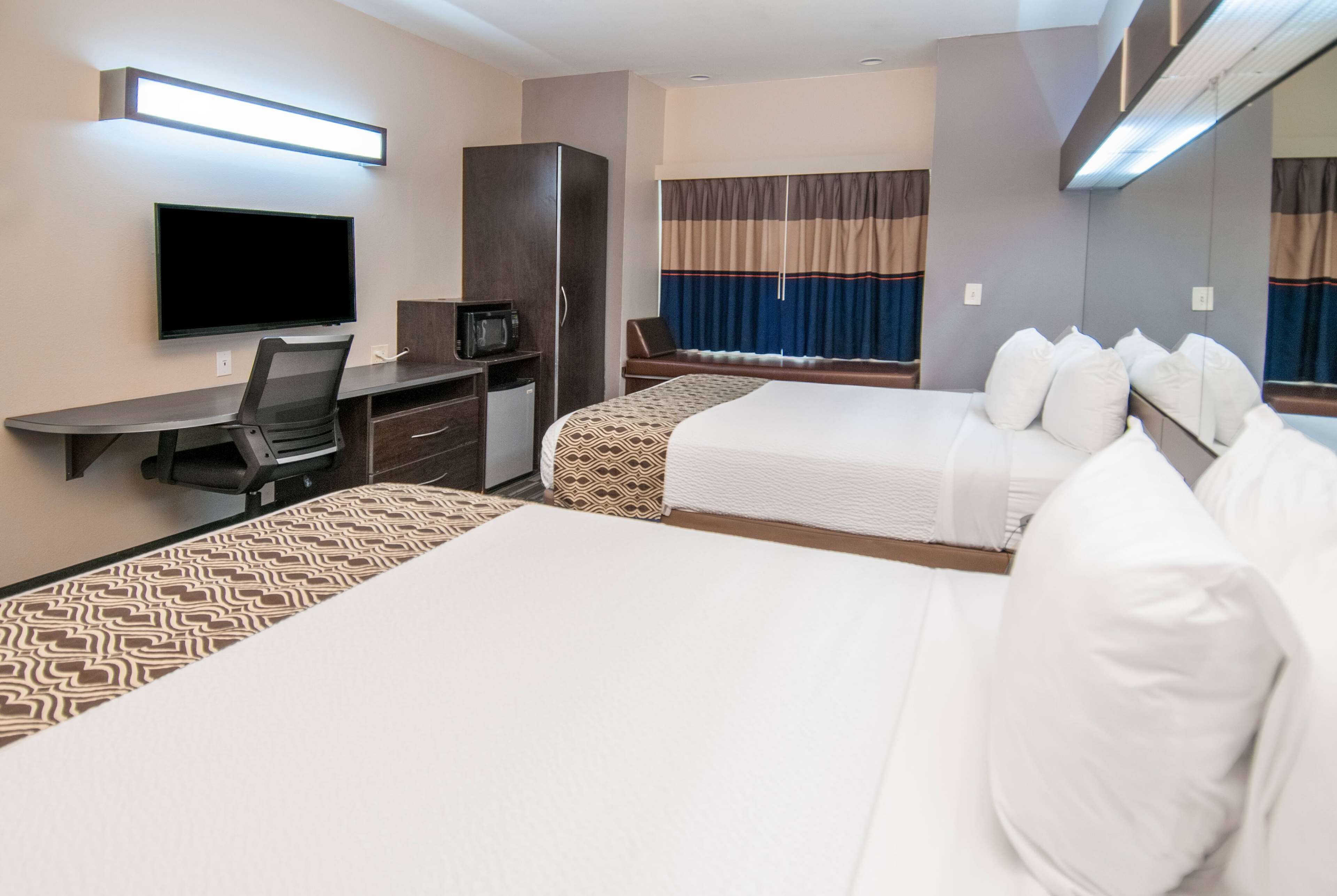 Ein Hotelzimmer mit Bett, Schreibtisch, Fernseher und Kleiderschrank.