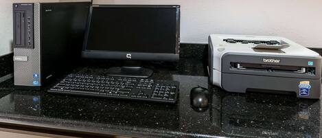 Een bureaub computer met een monitor, toetsenbord, muis en printer op een zwarte aanrechtblad.