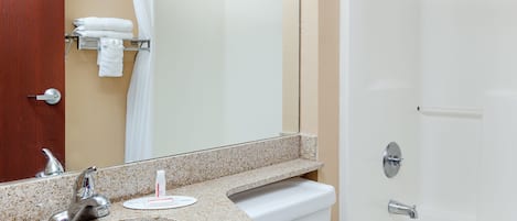 Un baño con lavamanos, espejo, toallero y bañera.