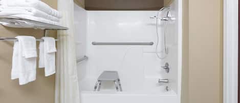 A modern bathroom with a walk-in shower, a towel rack, and a step stool.