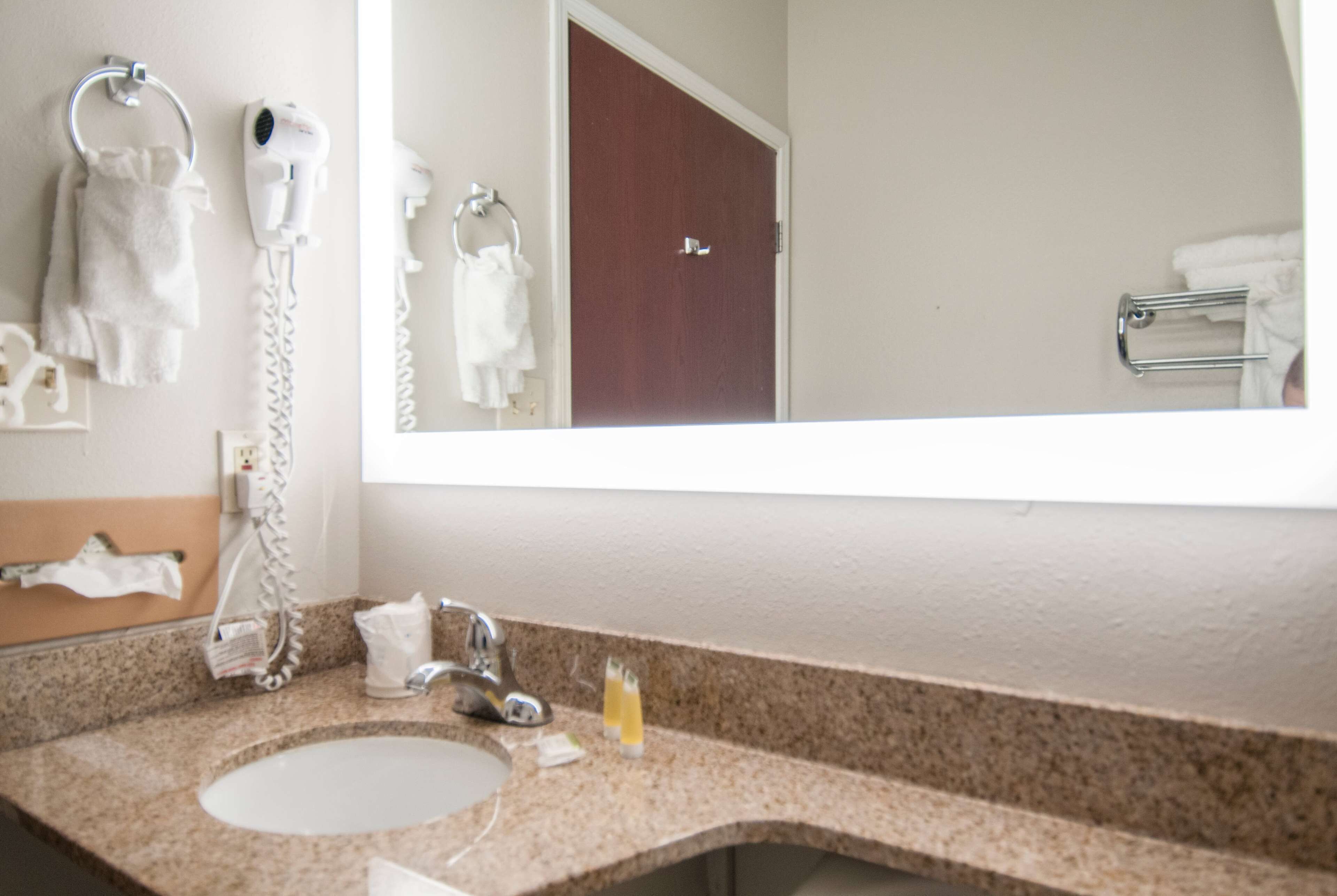 A bathroom with a sink, towel rack, and a mirror reflecting a door.