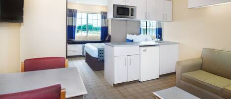 Um espaço compacto com cozinha compacta, área de jantar com mesa e cadeiras, e um sofá.
