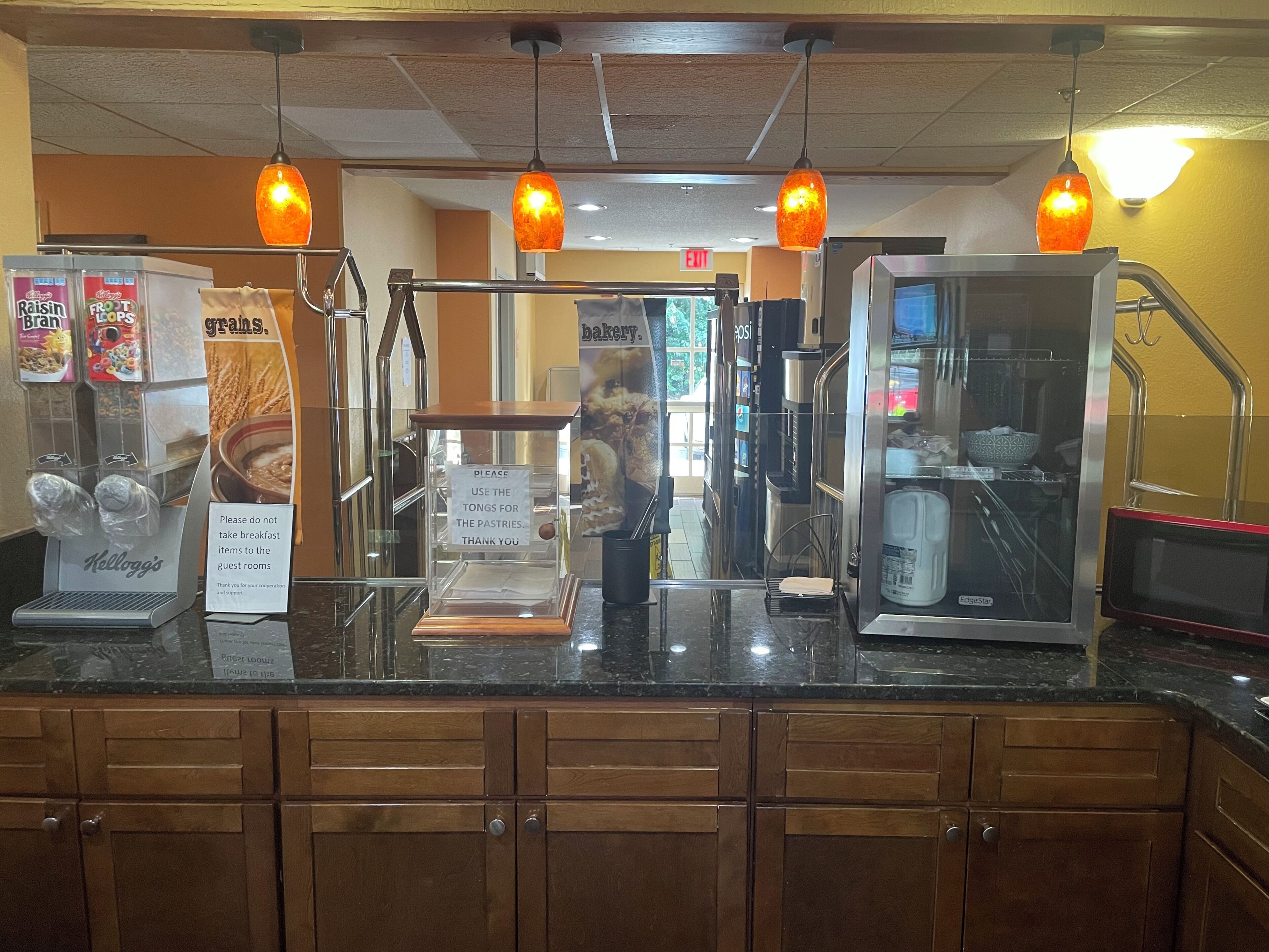 A breakfast bar with a coffee machine, a sign instructing not to take breakfast items to the guest rooms, and a display of cereal boxes.