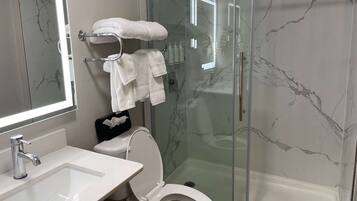 A bathroom with a glass-enclosed shower, a white sink, and a toilet.