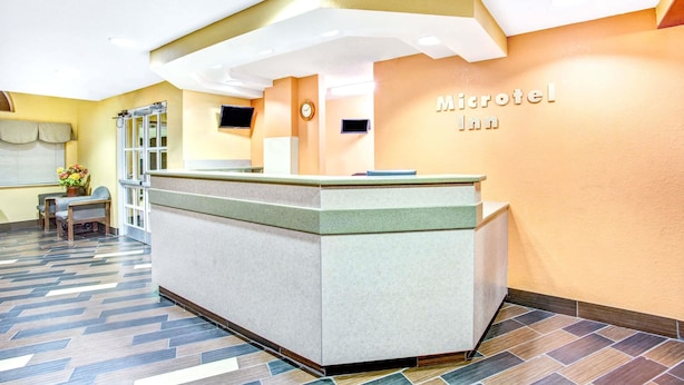 A reception area with a reception desk, a clock, and a wall-mounted sign that reads "Microtel Inn". - Microtel Inn by Wyndham Newport News Airport (Newport News)