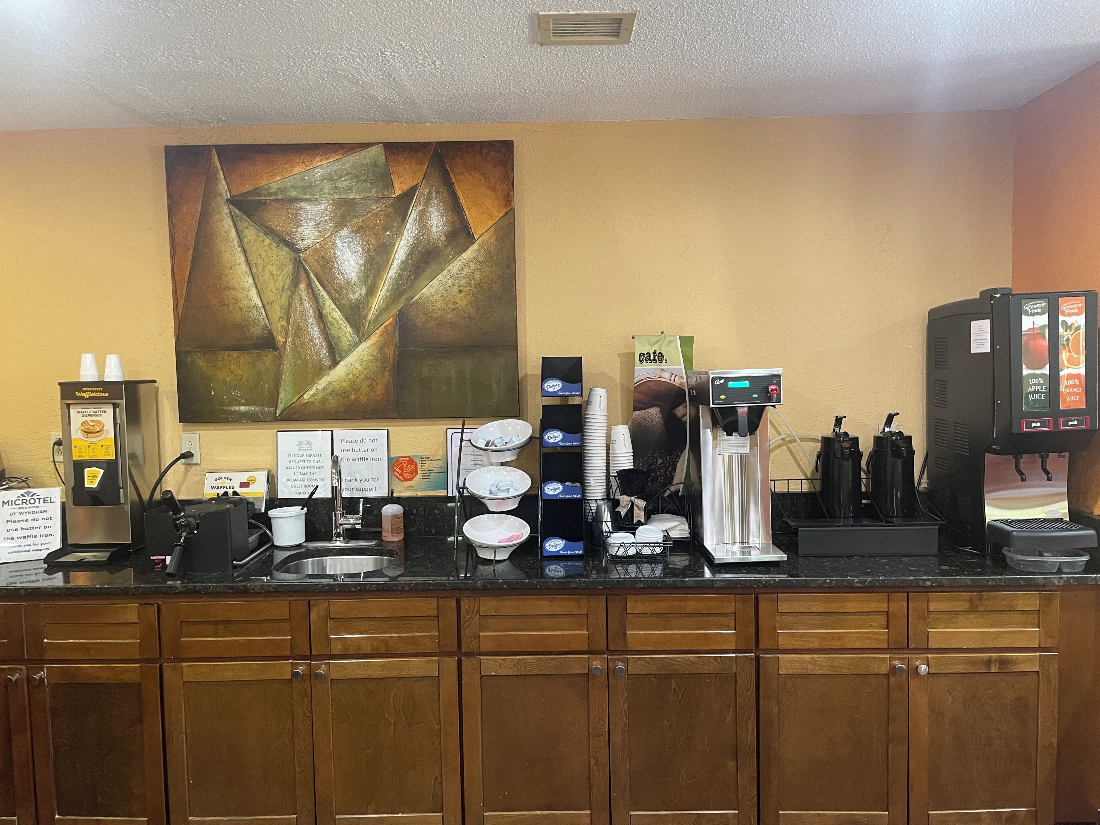 Mostrador de café con una plancha para gofres, máquina de café y dispensador de jugo.