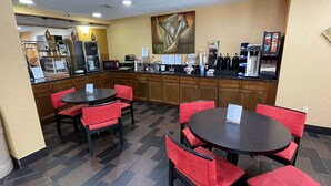 A hotel lobby with a coffee bar, seating area, and a large painting on the wall. - Microtel Inn by Wyndham Newport News Airport (Newport News)