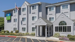 A multi-story hotel with a modern design, featuring a prominent SureStay logo and an American flag. - SureStay by Best Western Sacramento South Natomas (Sacramento)