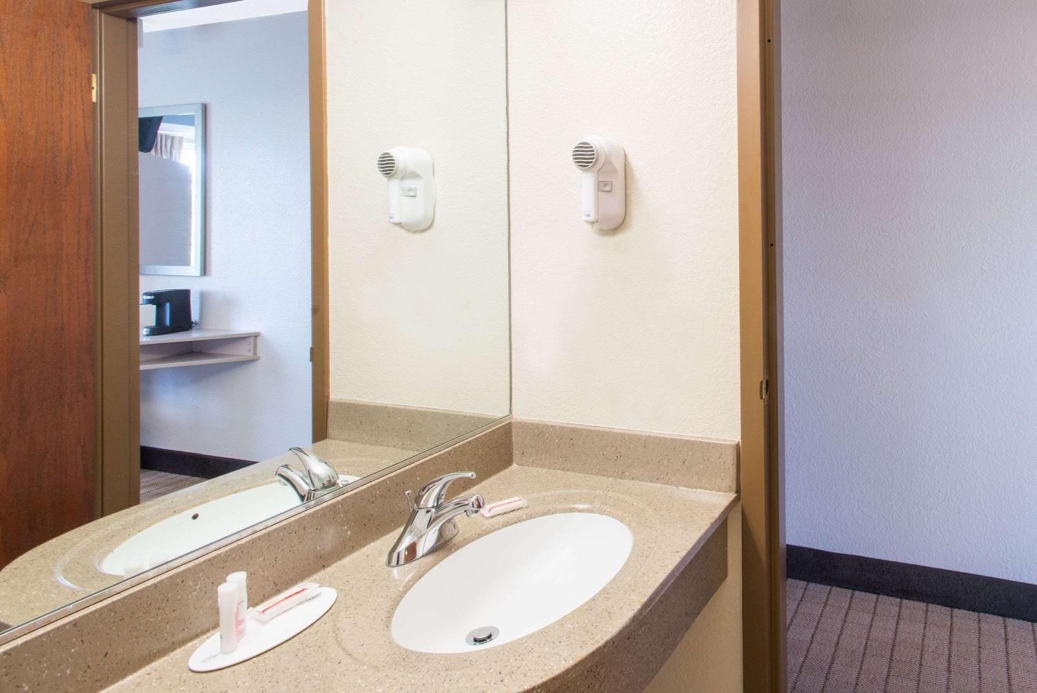 A bathroom with two sinks, a mirror, and two wall-mounted hair dryers.