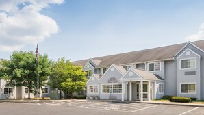 A two-story building with a symmetrical facade, a central entrance, and a parking lot with marked spaces.