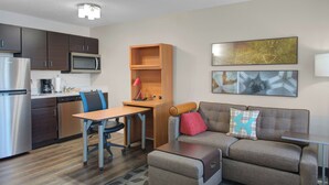A compact living space with a kitchenette, a sofa, a coffee table, and a desk. - TownePlace Suites by Marriott Wichita East (Wichita)