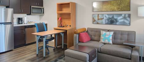 A compact living space with a kitchenette, a sofa, a coffee table, and a desk.