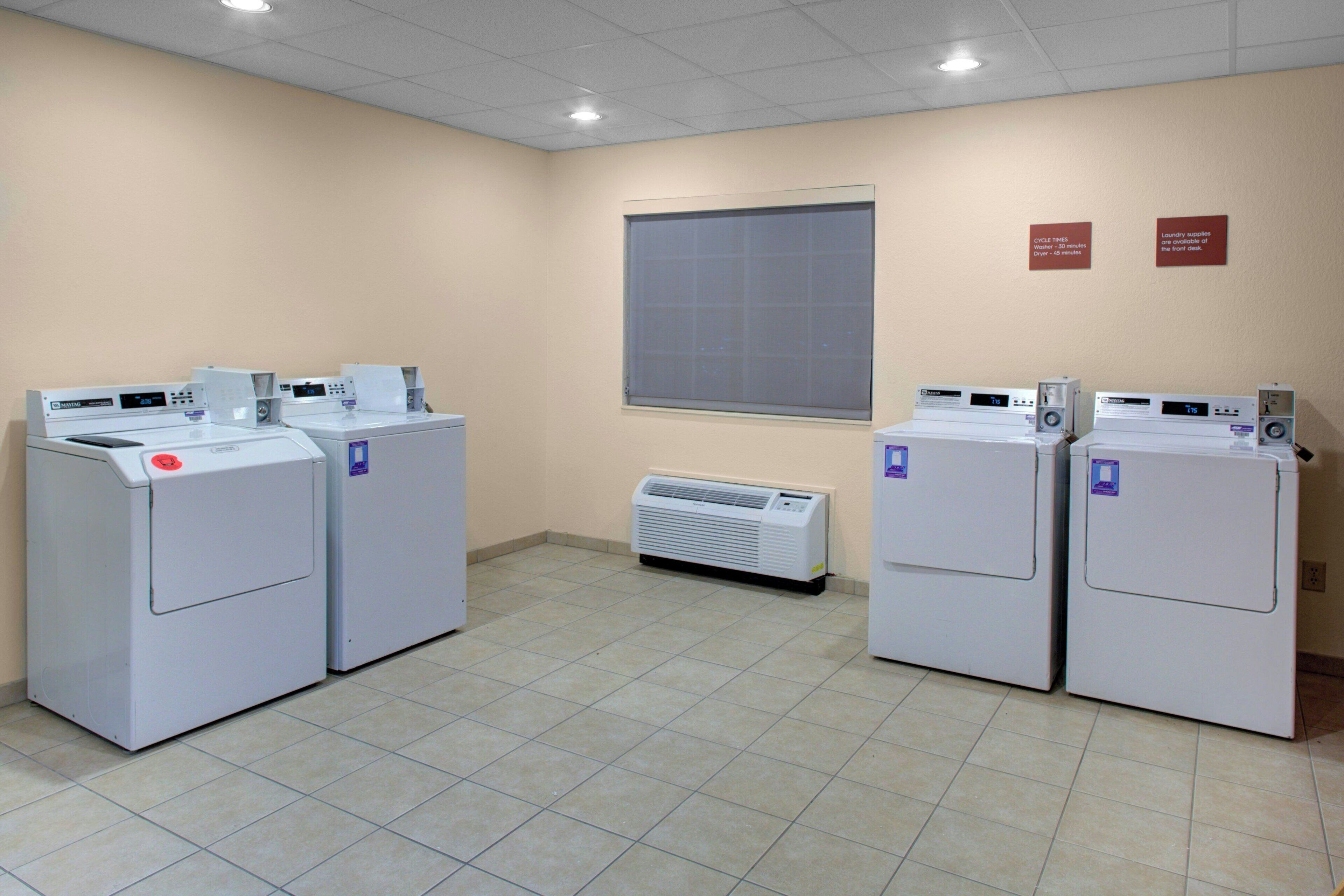 A laundry facility with four washing machines and a large window.