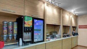 A breakfast area with a self-service beverage dispenser, a refrigerator stocked with beverages, and a coffee machine. - TownePlace Suites by Marriott Wichita East (Wichita)