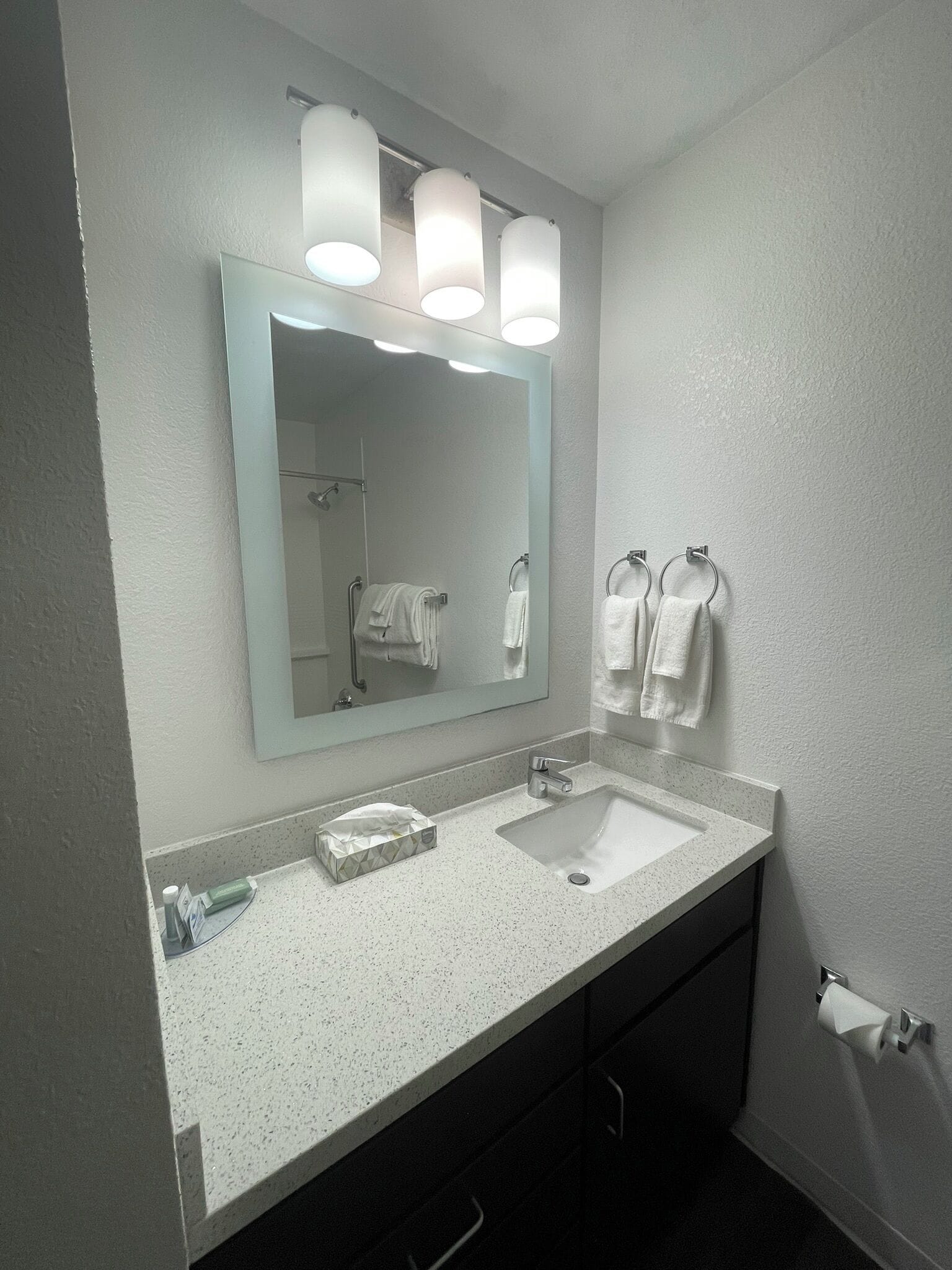 Een badkamer met een witte wastafel, een spiegel en twee handdoeken aan haken.