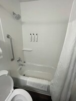 Un baño con bañera, inodoro, ducha y pasamanos.