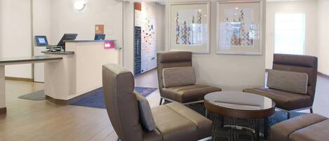 A lobby with a reception desk, seating area with chairs and a table, and artwork on the walls.