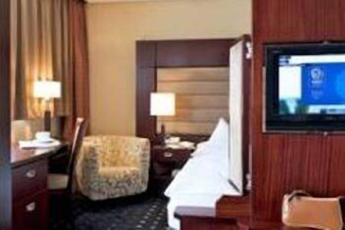 A hotel room with a bed, a desk, a chair, a television, and a window.