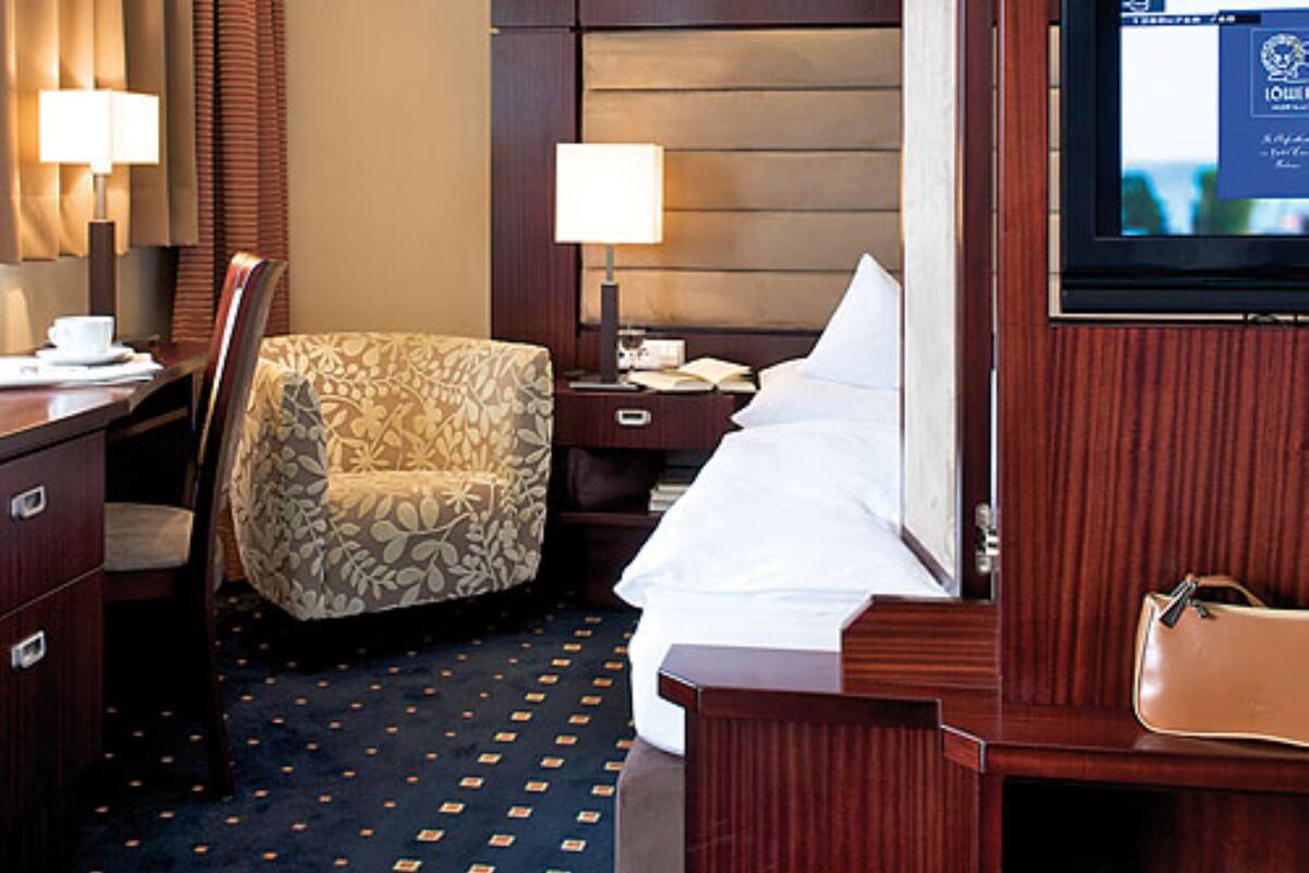 A hotel room with a bed, a desk, a chair, a television, and a minibar.
