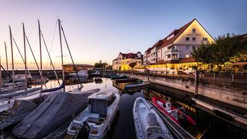 A marina with boats docked, a hotel named Hotel Lƶwen, and a calm waterfront setting.