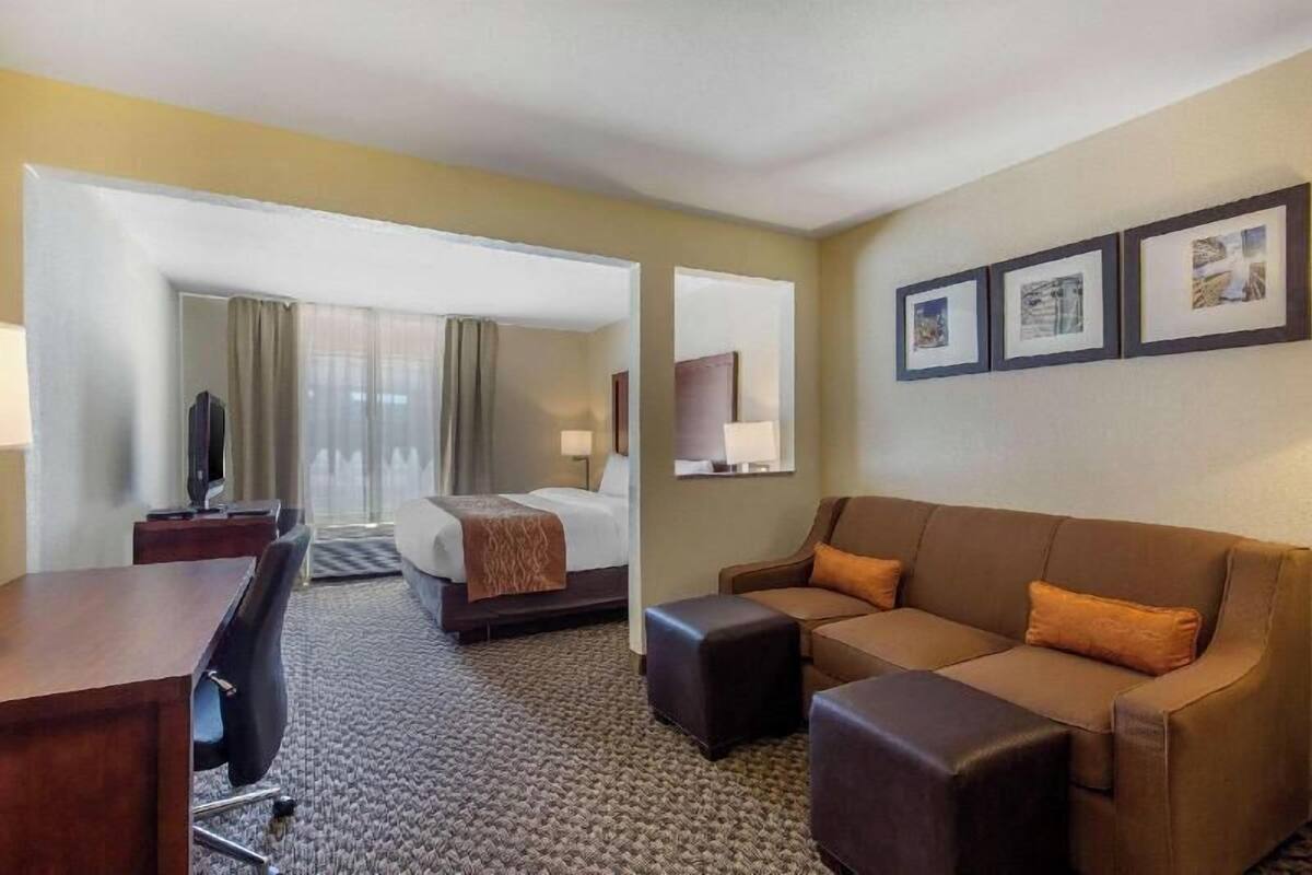 A hotel room with a bed, a sofa, a desk, and a television.