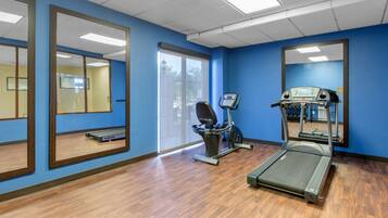 A fitness room with a treadmill, exercise bike, and large mirrors on blue walls.