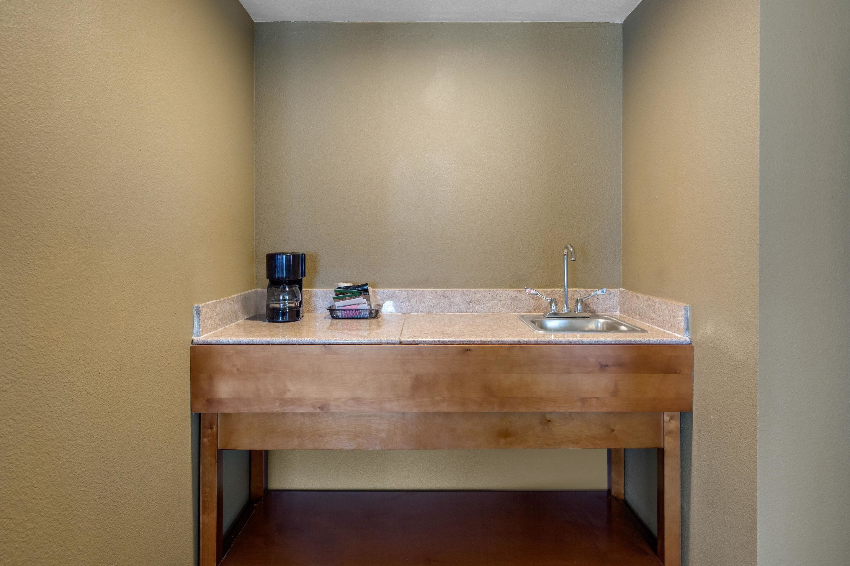 A small bathroom with a wooden vanity, a sink, and a coffee maker.