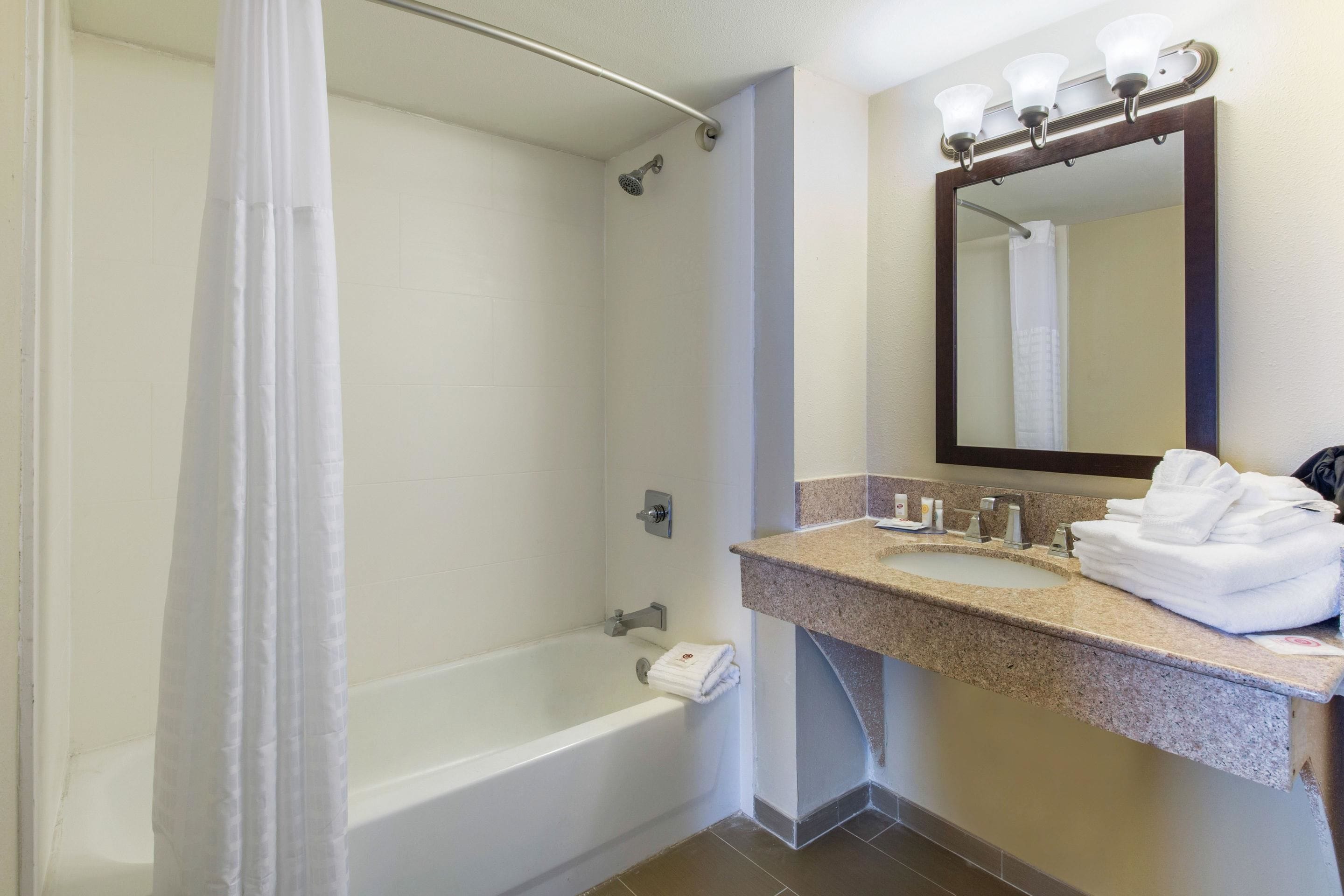 A bathroom with a bathtub, a sink with a mirror above it, and a shower curtain.